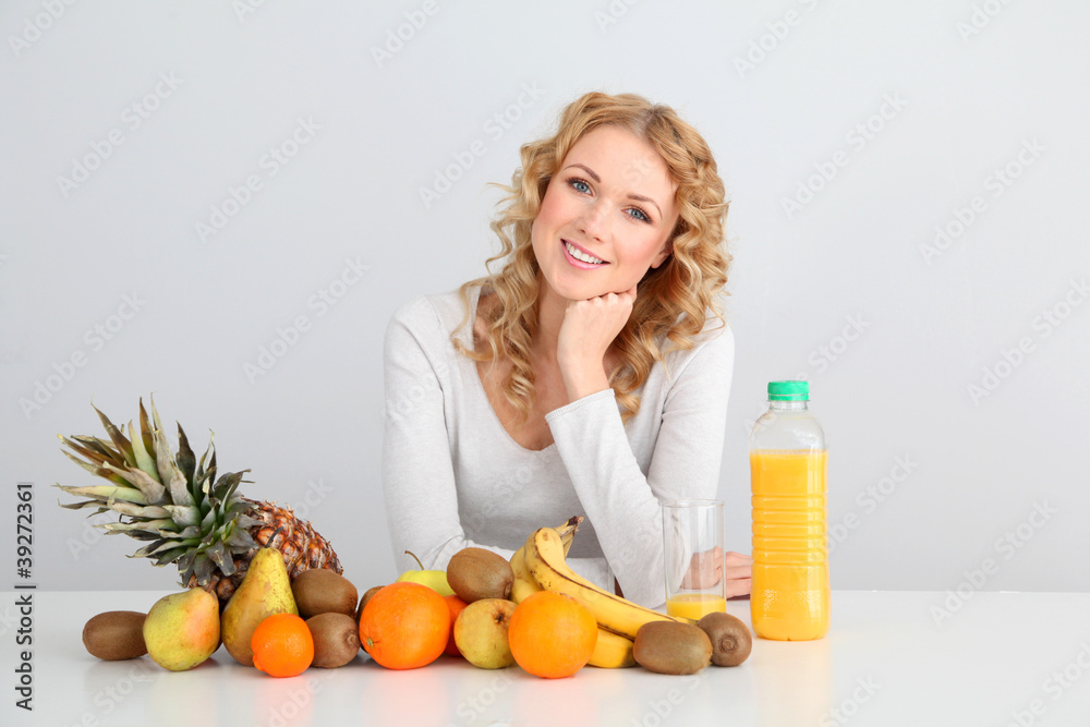 Smiling blond woman sitting with fruits on table Smiling blond woman sitting with fruits on table