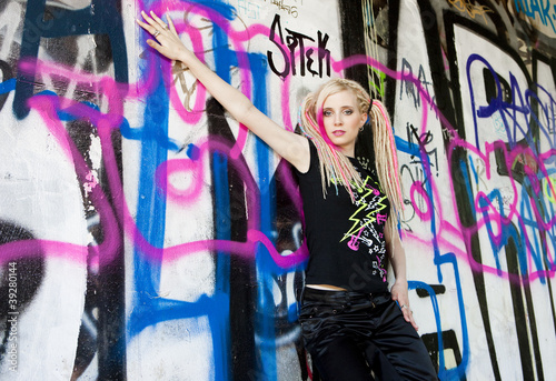 portrait of young woman standing at graffitti wall