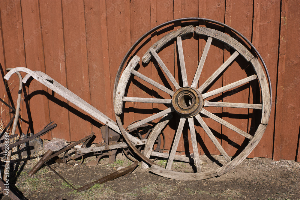 Obraz premium red barn with wheel and plow
