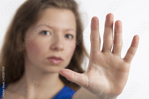 Junge Frau mit zum Stopp erhobener Hand im Vordergrund photo