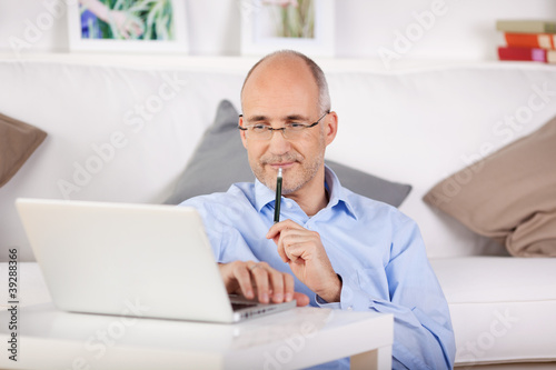 zufriedener mann sitzt zuhause am laptop