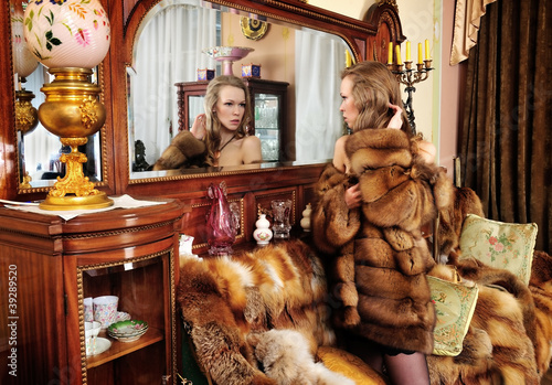 woman in fur coat at the mirror in Luxurious classical interio