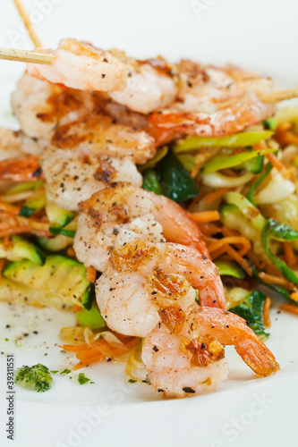 Shrimp on skewers on top of assortment of vegetables