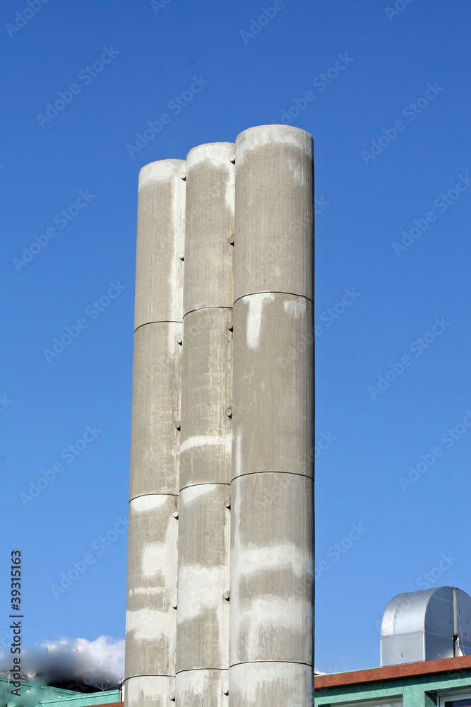 three high concrete chimney with a backdrop of sky