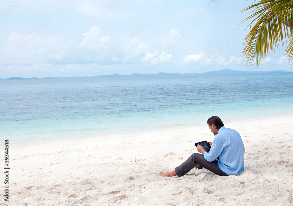 Business man sitting and working on the beach with Ipad Business man sitting and working on the beach with Ipad