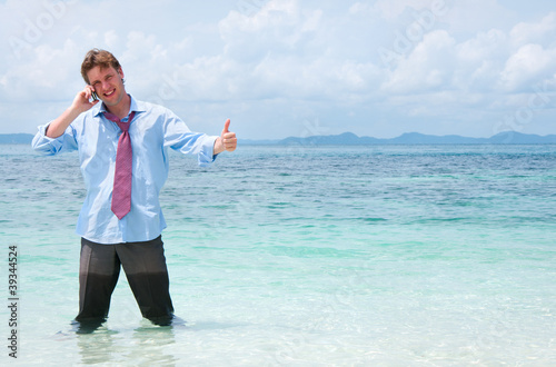 Business man calling by cell phone on the beach