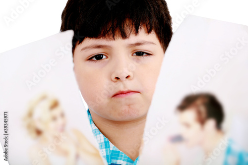 Upset boy standing in front pcture of parents with problems agai