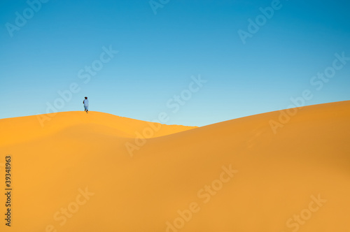 Wallpaper image of sand dunes with a Tuareg man on the horizon