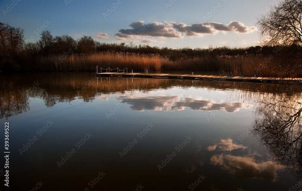 Beautiful late evening sunset landscape over jetty on lake