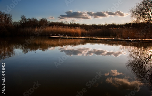 Beautiful late evening sunset landscape over jetty on lake