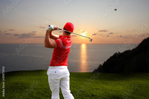 Man playing golf against sunset over sea