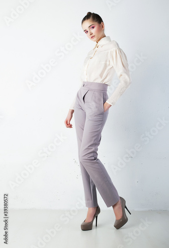 Young pretty brunette woman in white shirt and blue trousers photo