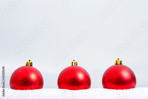 Three red Christmas ornaments in the snow