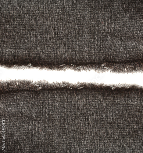 Piece of black jeans fabric with fringe on white