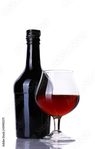 Glass of brandy and bottle isolated on white