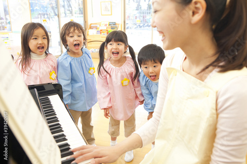 幼稚園教諭のピアノに合わせて歌う幼稚園児