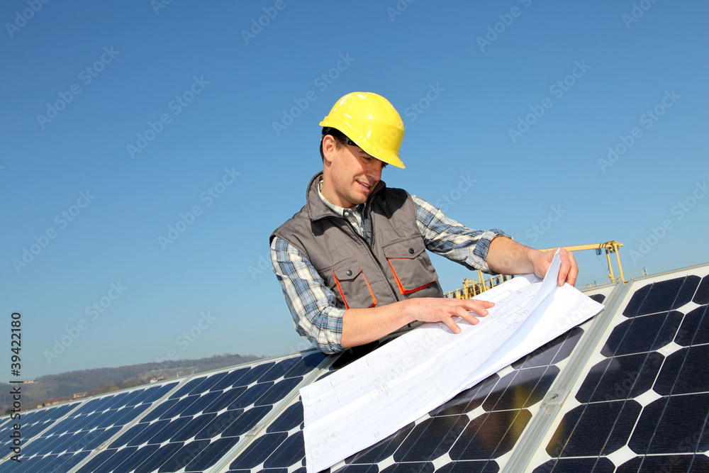 Man standing by solar panels with construction plan