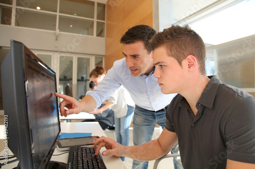 Teacher and student working on computer
