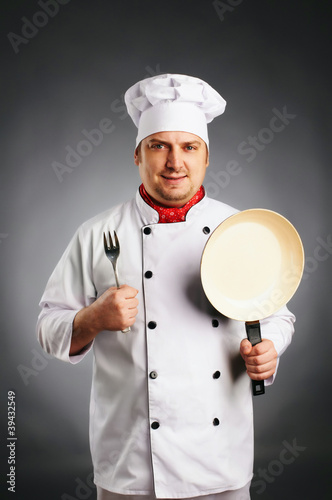 smiling cook with knife and pan in his hands