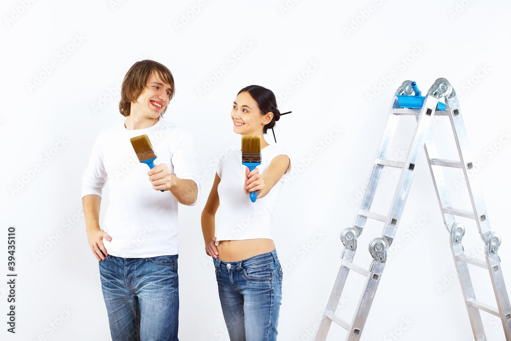 Young couple with paint brushes together Young couple with paint brushes together