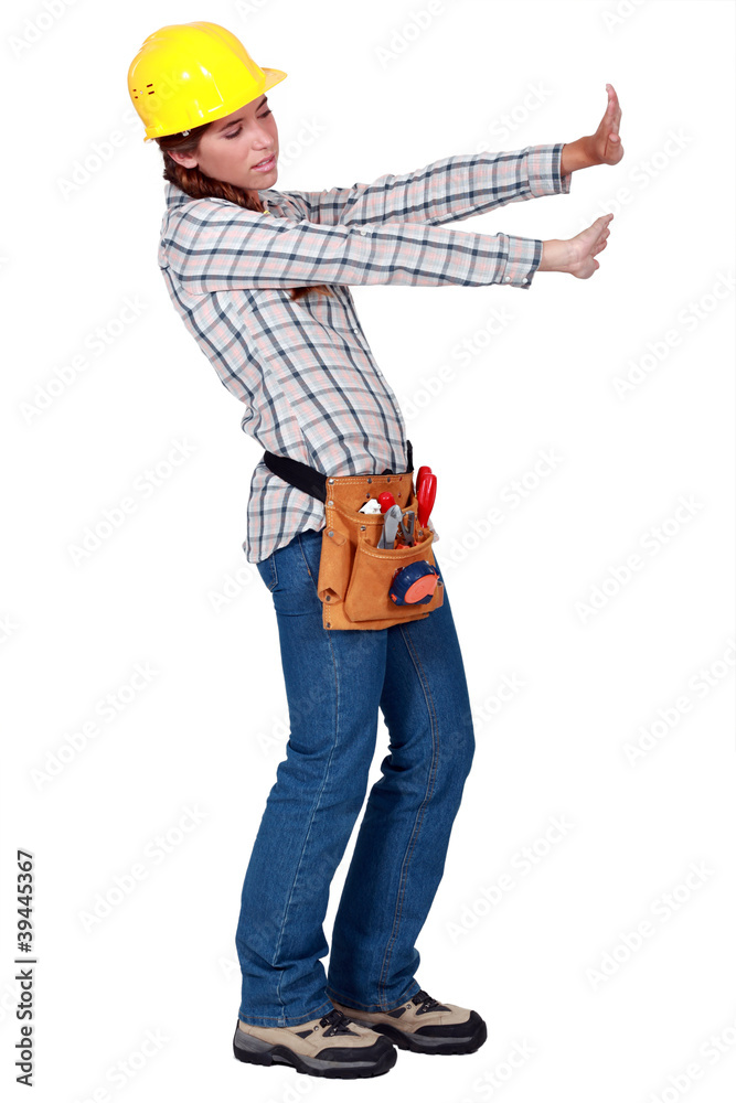 Tradeswoman pushing up against an invisible wall Tradeswoman pushing up against an invisible wall