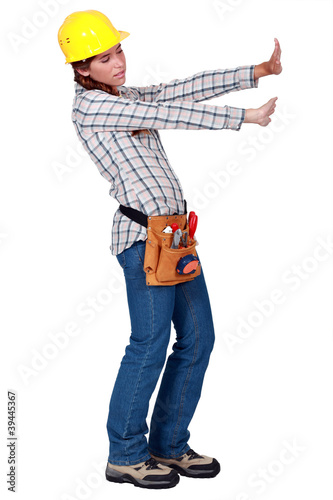 Tradeswoman pushing up against an invisible wall photo