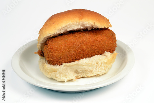 Roll with crispy calf croquette on a white context roll.