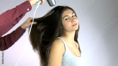 Hairdresser hairdrying girl's hair photo