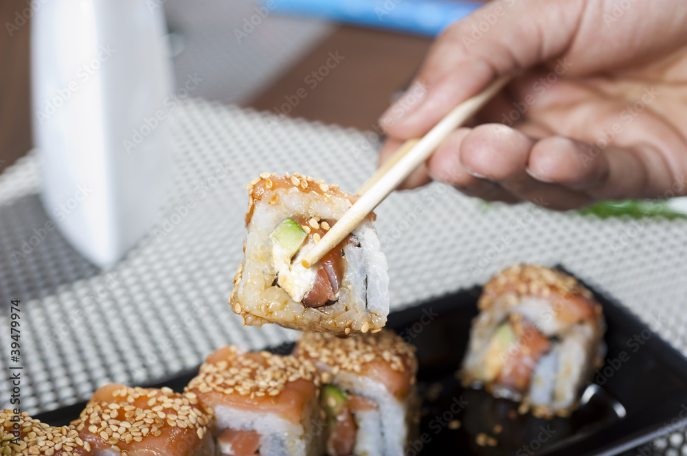 Hand using chopsticks with sushi Hand using chopsticks with sushi