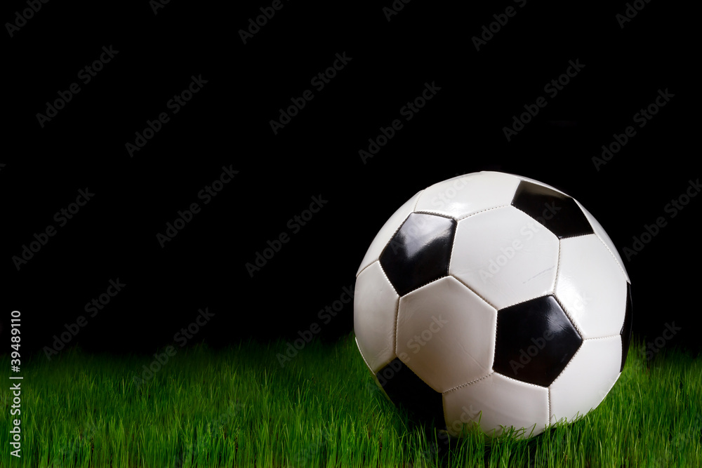 Soccer ball on grass over black background