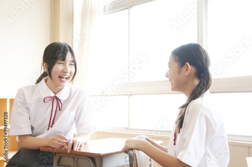 教室で会話している2人の女子中学生