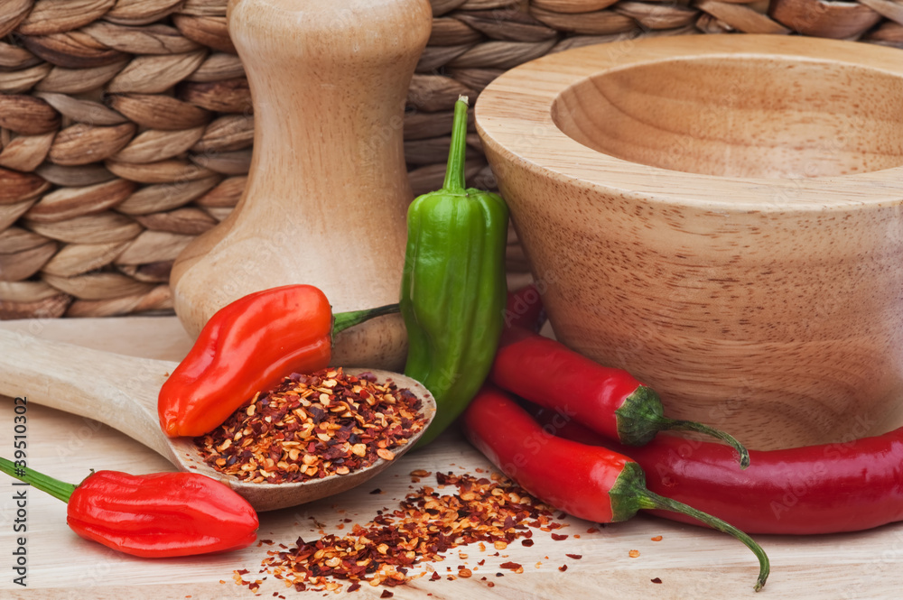 Crushed and whole chilli peppers in rustic kitchen setting Crushed and whole chilli peppers in rustic kitchen setting