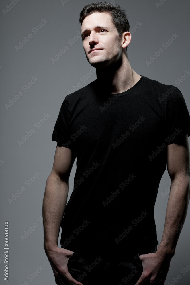 Man in black t-shirt posing on gray background.