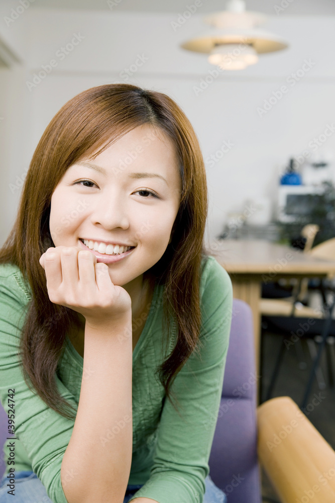 椅子に座りながら頬杖をつき笑っている女性 椅子に座りながら頬杖をつき笑っている女性