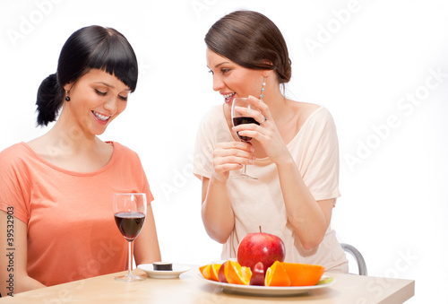 Two women eating fruits and drinking red wine