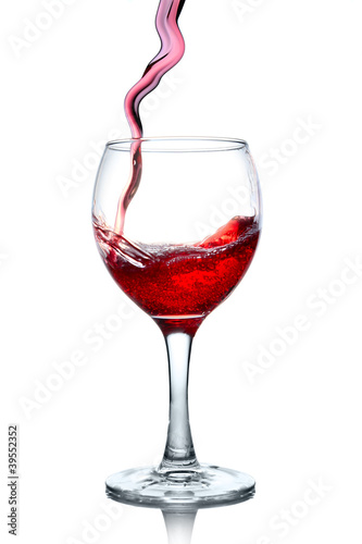 Red wine pouring in glass isolated on white