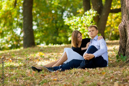 Romantic young couple sitting together at park on the grass