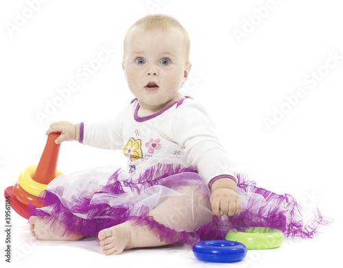 The little girl sits with toys on a white background