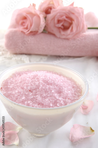 Bowl of bath salt with pink rose on towel