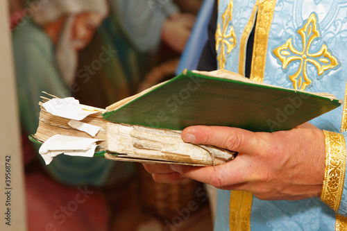 Bible in hands of holy father in church photo