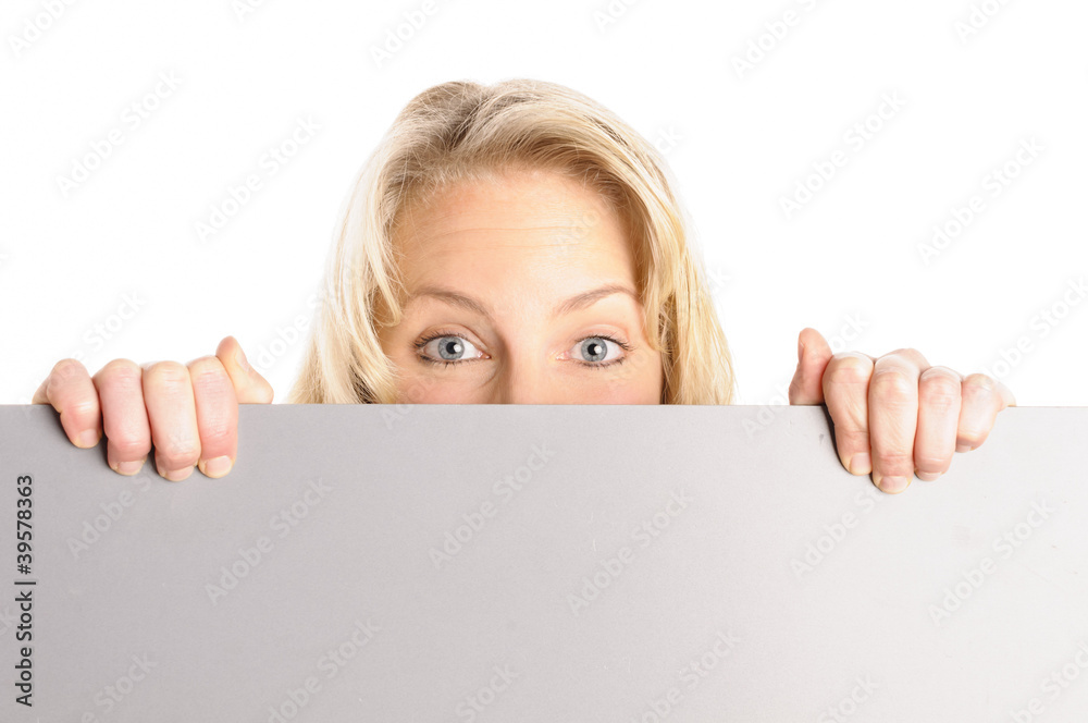Attraktive junge Frau schaut hinter einer grauen Wand hervor Attraktive junge Frau schaut hinter einer grauen Wand hervor