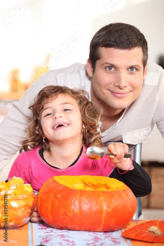 a father and his little girl laughing and eating a pumpkin