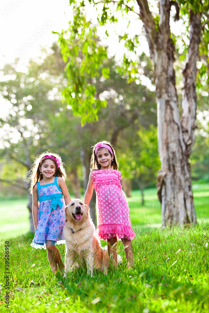 Obraz premium Two happy little girls and a golden retriever