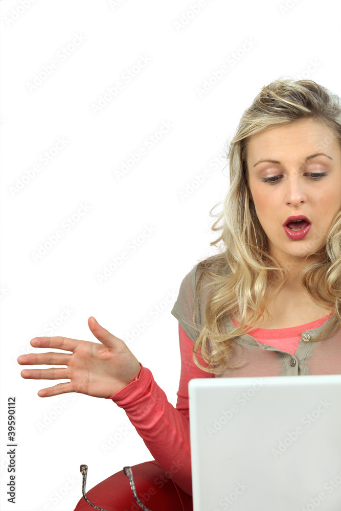 Naklejka premium Girl with expression of surprise using laptop computer