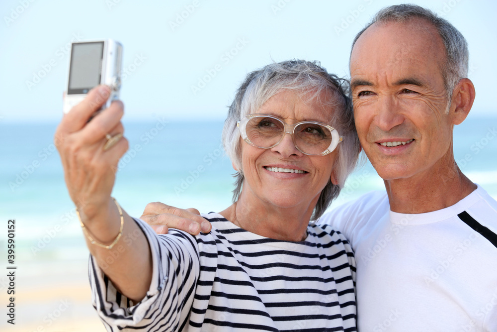 Older couple taking their own photograph at the beach Older couple taking their own photograph at the beach