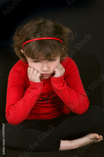 little girl pouting with face resting on hands