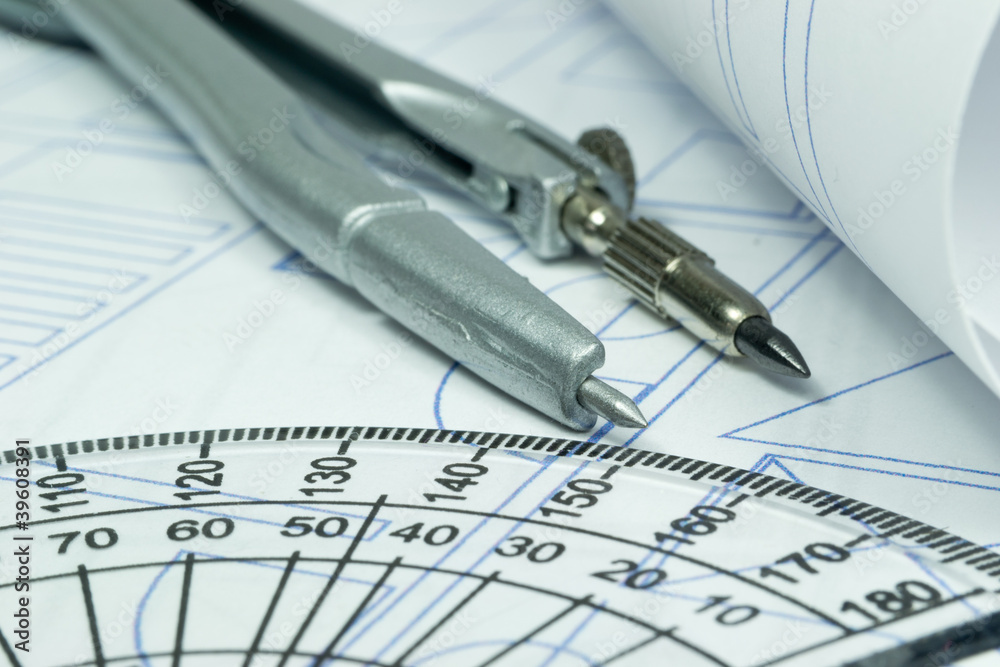Close up image of a compass lying on building plans Close up image of a compass lying on building plans