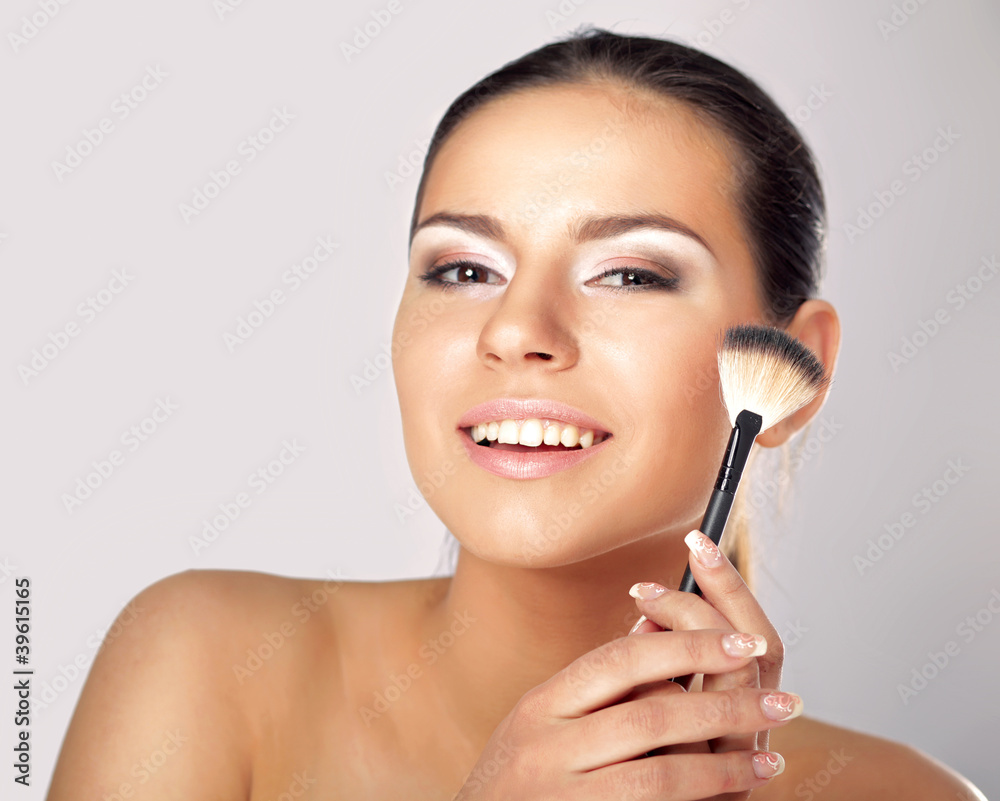 Portrait of attractive young adult woman applying blusher Portrait of attractive young adult woman applying blusher