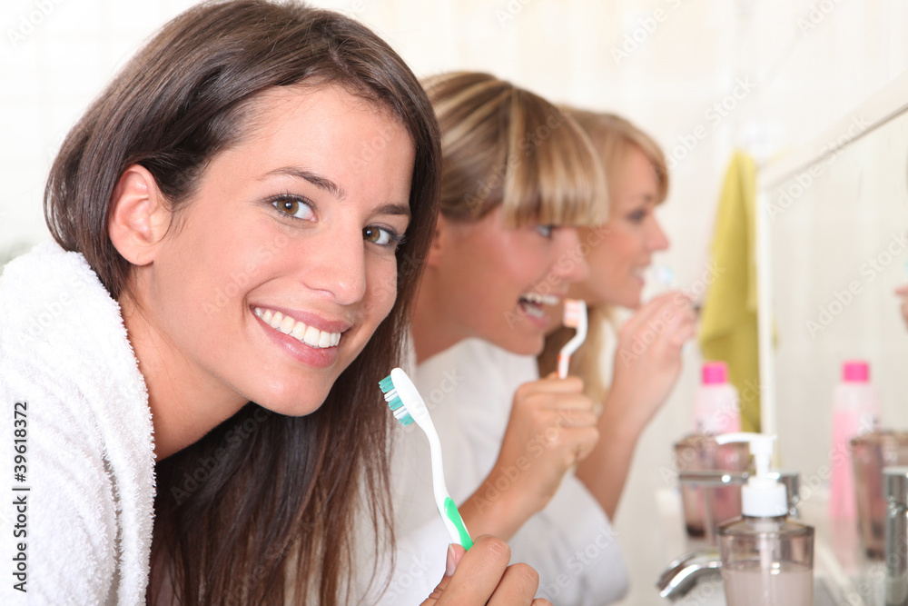 Three young women brushing their teeth Three young women brushing their teeth