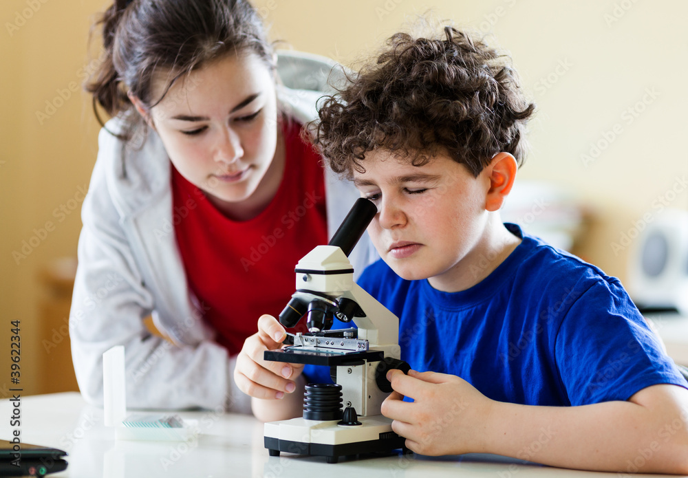 Girl and boy examining preparation under the microscope Girl and boy examining preparation under the microscope